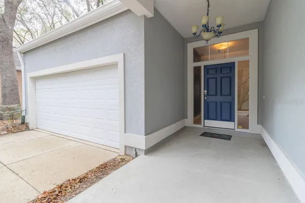 a view of an empty room with window and chandelier fan