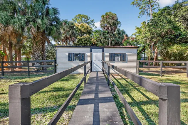 a backyard of a house with large trees and outdoor seating