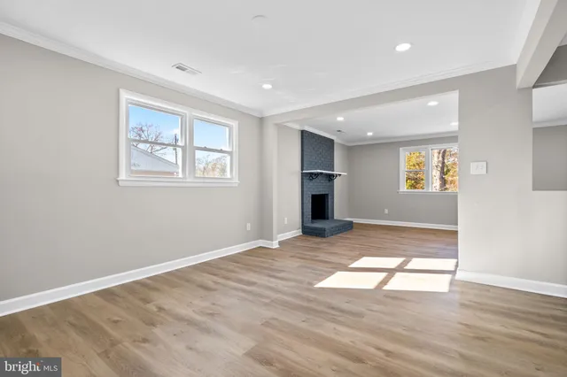 a view of an empty room with window and wooden floor