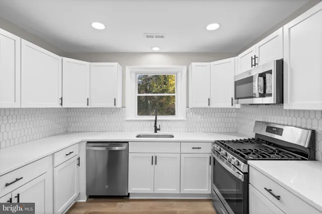 a kitchen with granite countertop white cabinets white stainless steel appliances a sink and a window