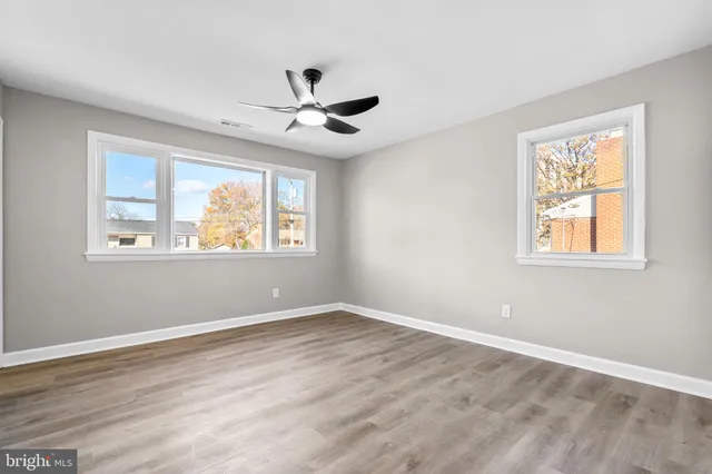 a view of empty room with wooden floor and fan