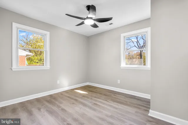 a view of empty room with wooden floor and ceiling fan