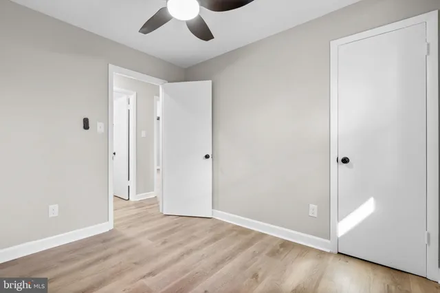 an empty room with wooden floor and ceiling fan