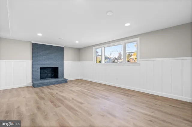 a view of an empty room with wooden floor and a fireplace
