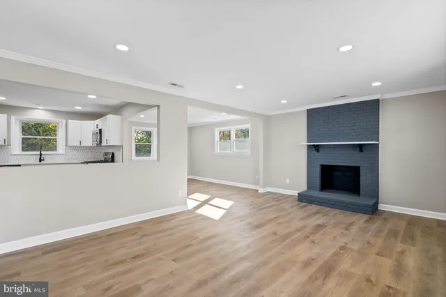 an empty room with wooden floor fireplace and windows