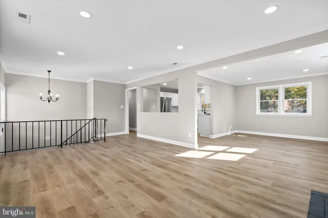 a view of an empty room with wooden floor and windows