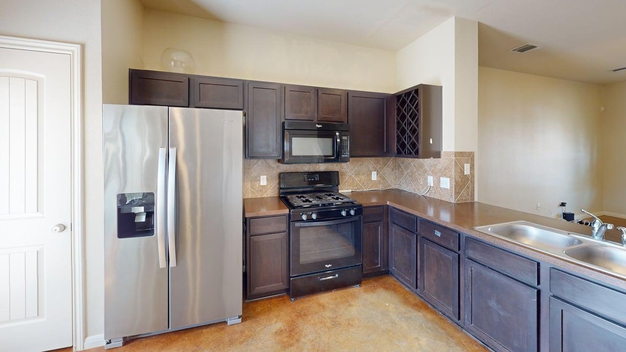4621 Kind Way, Unit 271 Austin, TX 78742 - Photo 3 of 11 Kitchen with black appliances, dark wood finish cabinetry, and decorative backsplash
