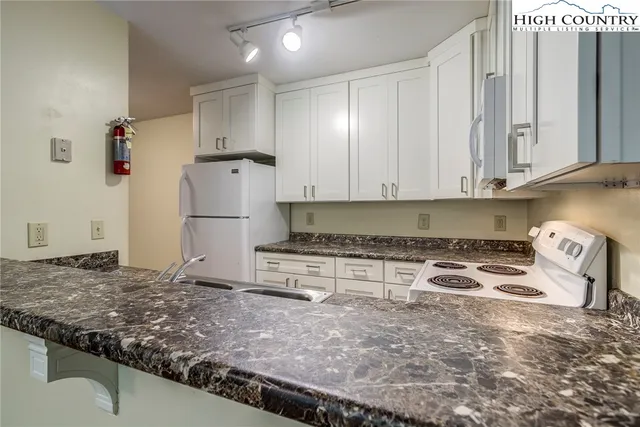 a kitchen with granite countertop a sink stove and refrigerator