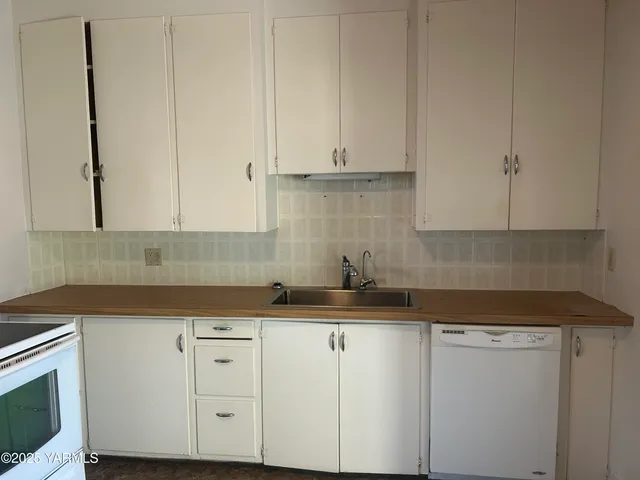 a kitchen with granite countertop white cabinets and white appliances