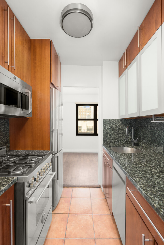 240 East 76th Street, Unit 8G Manhattan, NY 10021 - Photo 5 of 8 a kitchen with stainless steel appliances granite countertop a stove a sink and a microwave