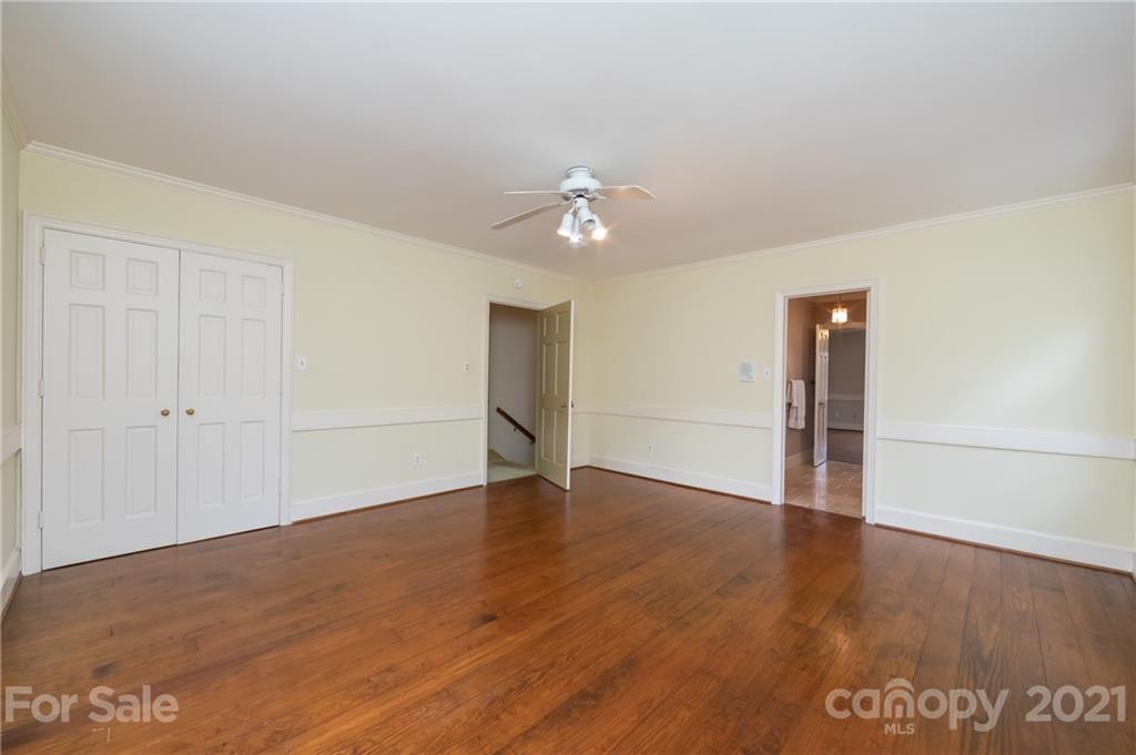 3229 Colony Road Charlotte, NC 28211 - Photo 30 of 44 an empty room with wooden floor chandelier fan and windows