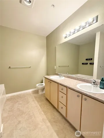 a spacious bathroom with a double vanity sink toilet and a mirror