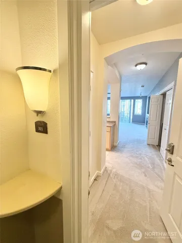 a view of a hallway with wooden floor and a bathroom