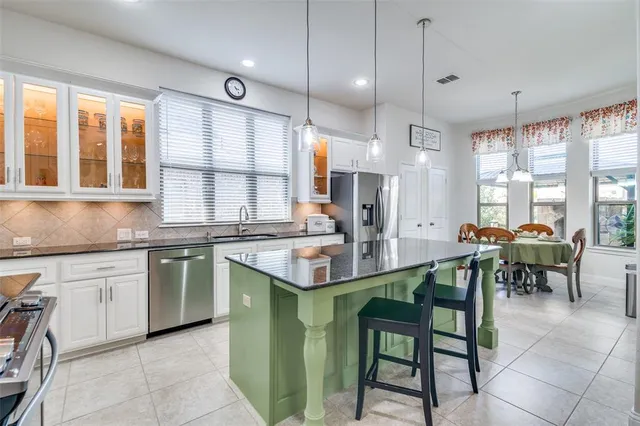 a kitchen with kitchen island granite countertop a table chairs sink and cabinets