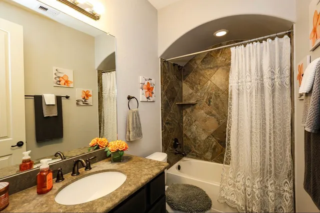 a bathroom with a granite countertop sink and a mirror a bathtub