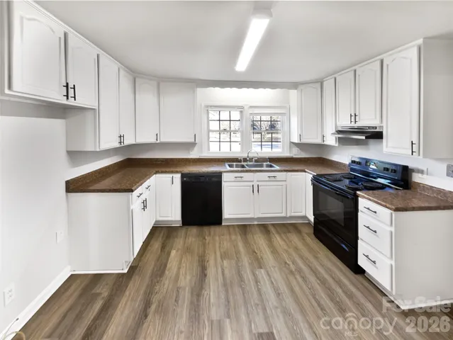 a kitchen with a sink a stove cabinets and a window