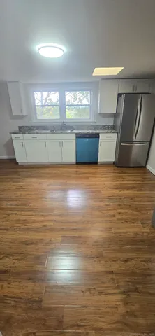 a view of kitchen and empty room with wooden floor