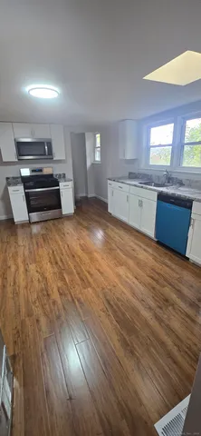 a kitchen with stainless steel appliances wooden floors and view living room