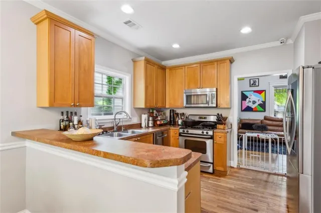 a kitchen with stainless steel appliances granite countertop a stove top oven a sink a dining table and chairs