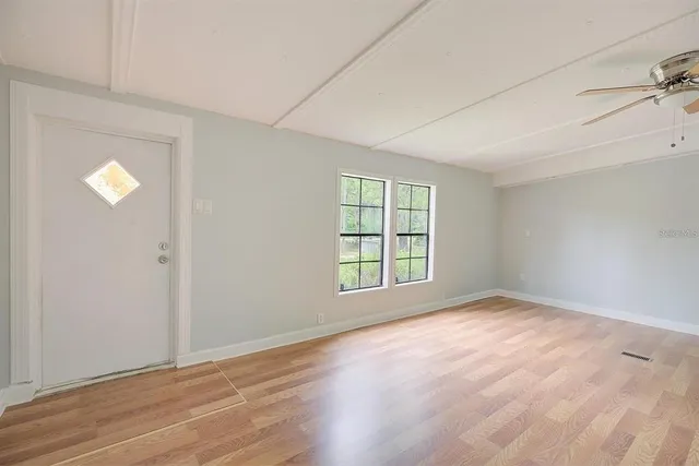 an empty room with wooden floor and windows