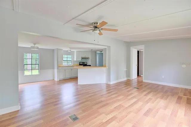a view of an empty room with window and wooden floor