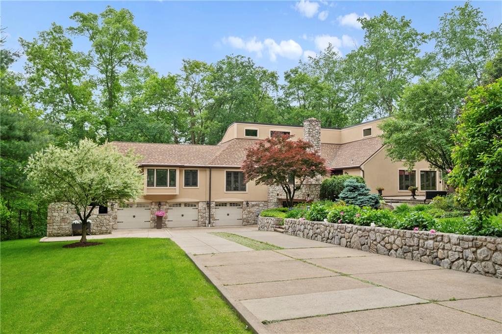 a front view of a house with a garden and trees
