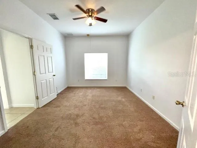 an empty room with windows and fan