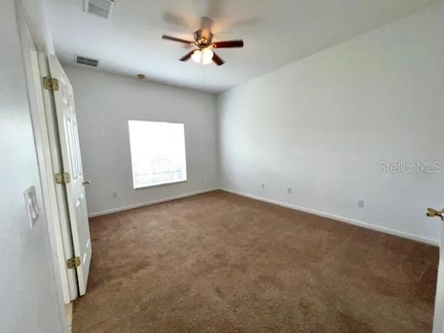 an empty room with windows and fan