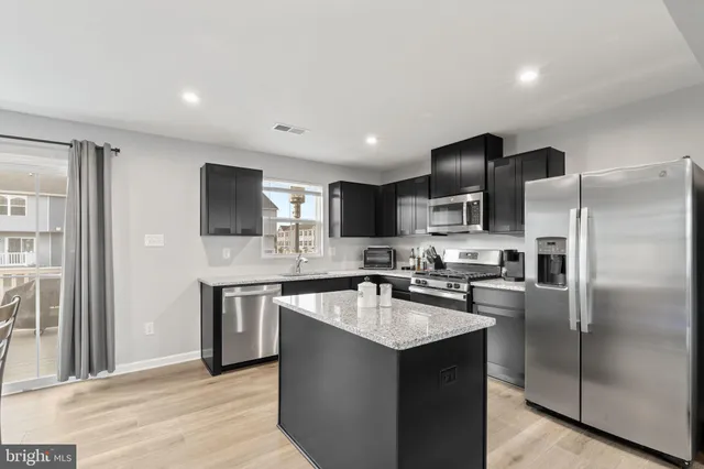 a kitchen with stainless steel appliances granite countertop a sink stove refrigerator and cabinets