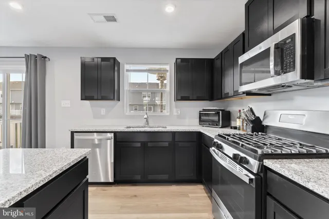 a kitchen with stainless steel appliances granite countertop a sink stove and microwave