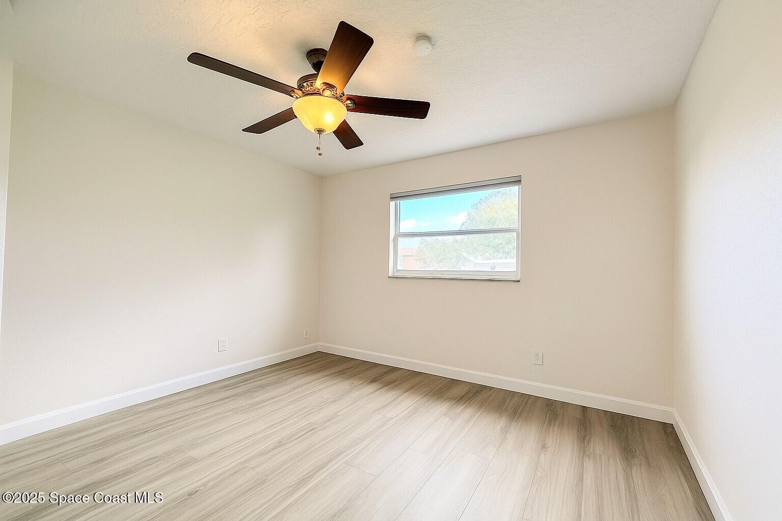 1021 Palmer Road Rockledge, FL 32955 - Photo 17 of 23 a view of a room with wooden floor and a ceiling fan