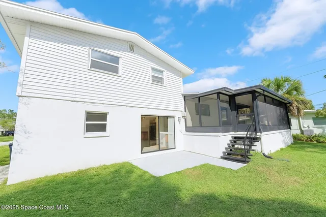 a view of a white house with a big yard and large tree