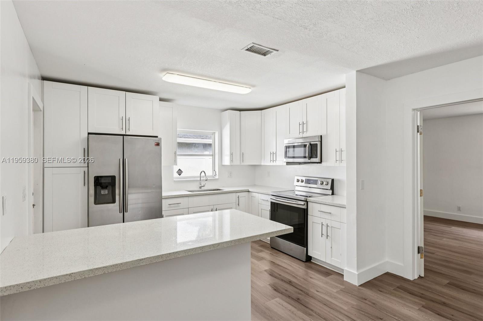 2720 Northeast 25th Terrace Boca Raton, FL 33431 - Photo 12 of 40 a large kitchen with cabinets stainless steel appliances and wooden floor