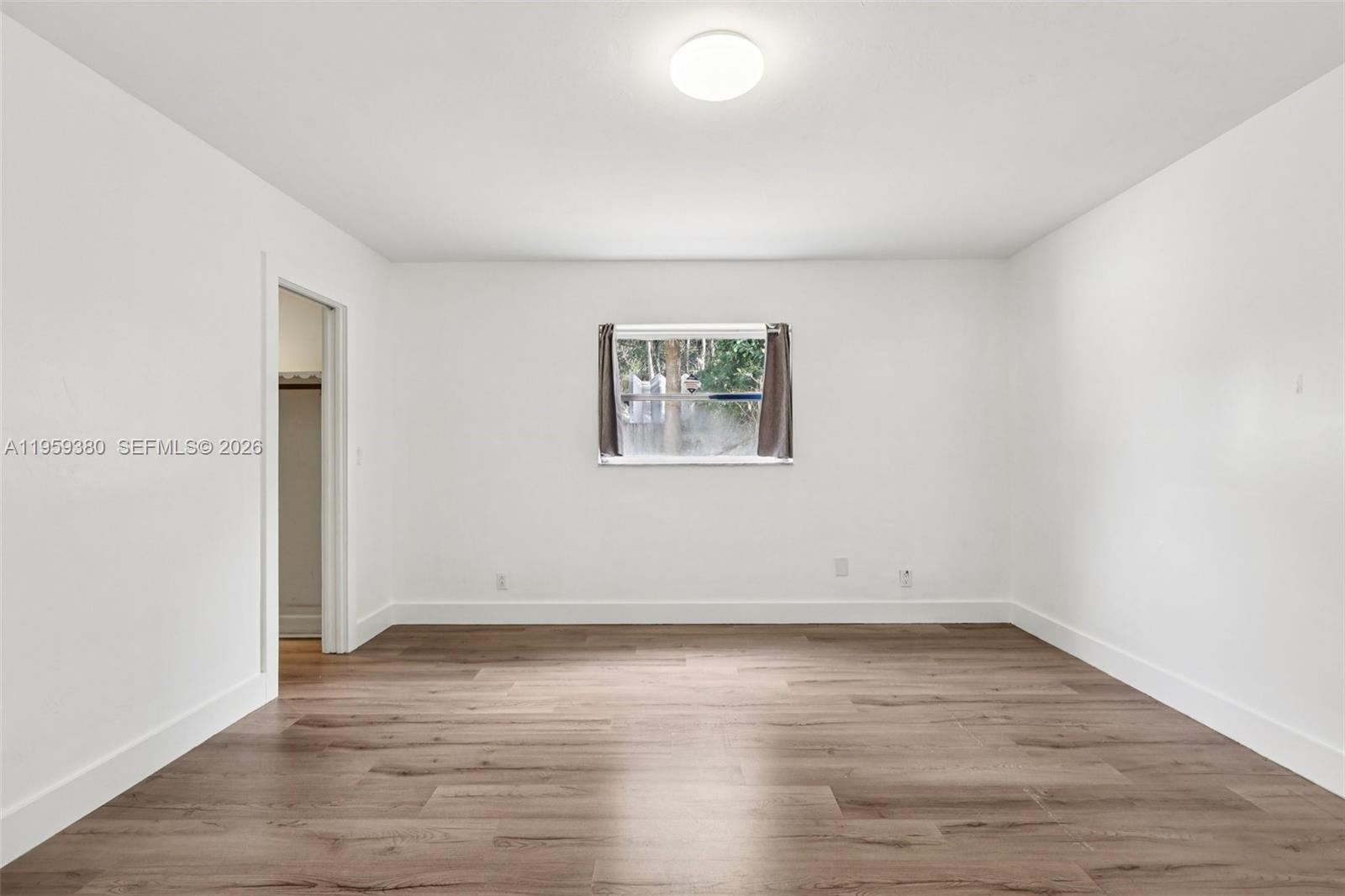 2720 Northeast 25th Terrace Boca Raton, FL 33431 - Photo 16 of 40 an empty room with wooden floor and window