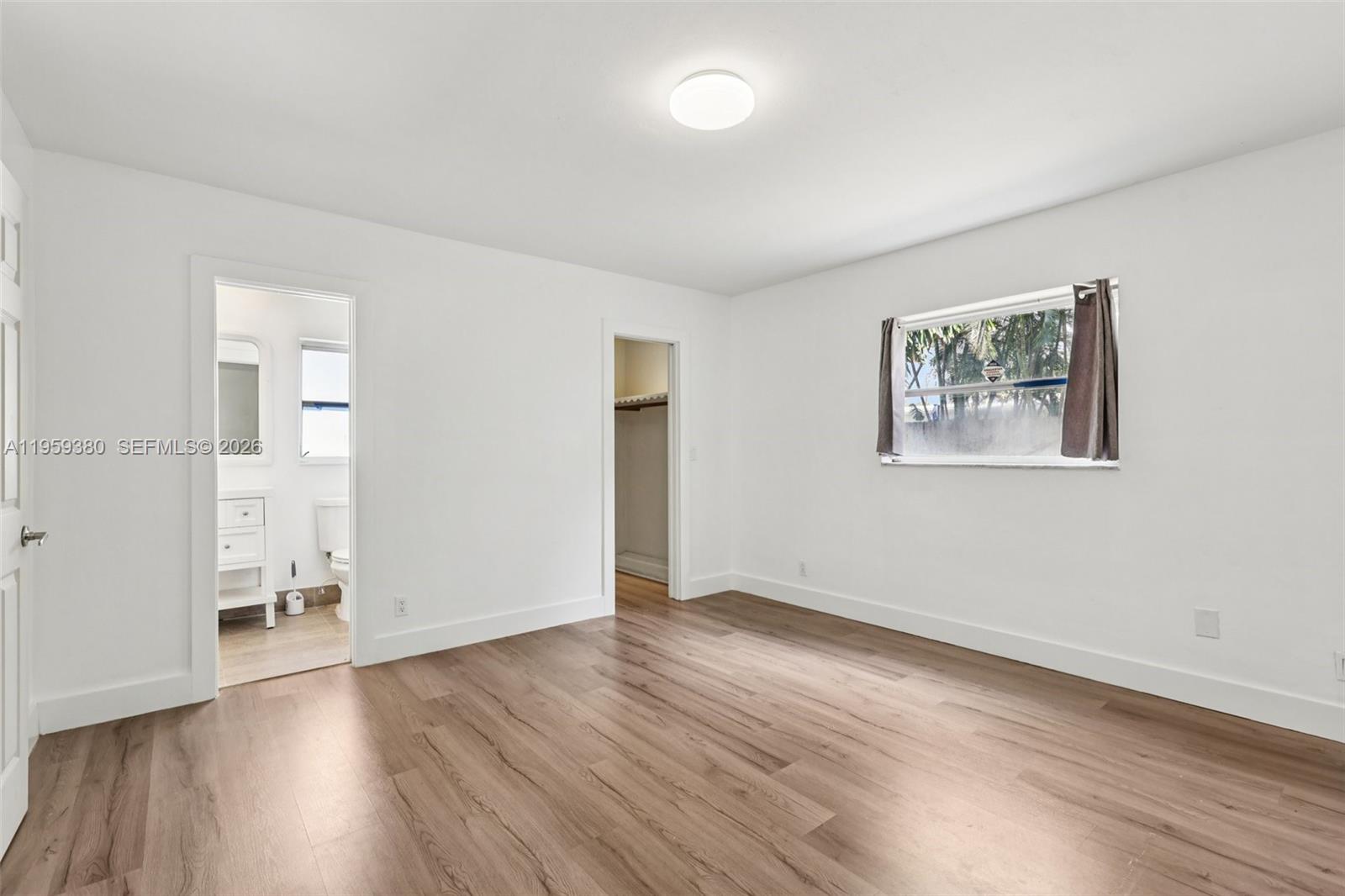 2720 Northeast 25th Terrace Boca Raton, FL 33431 - Photo 17 of 40 an empty room with wooden floor and windows