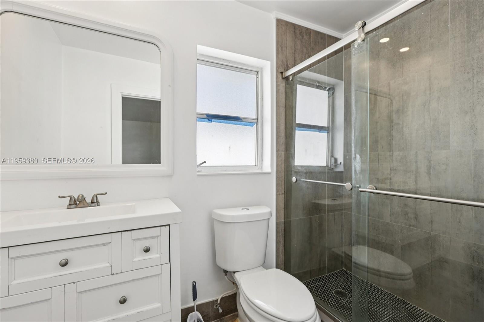 2720 Northeast 25th Terrace Boca Raton, FL 33431 - Photo 21 of 40 a bathroom with a toilet a sink a mirror and a shower