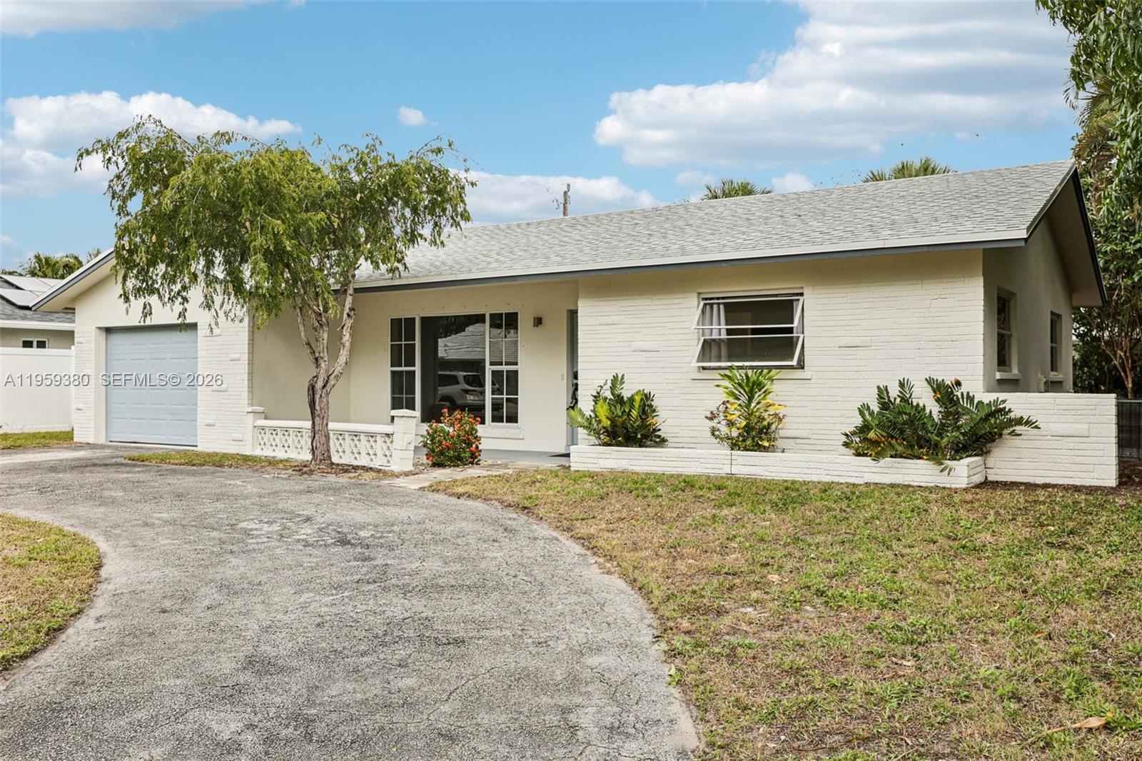 2720 Northeast 25th Terrace Boca Raton, FL 33431 - Photo 3 of 40 a front view of a house with a yard and garage