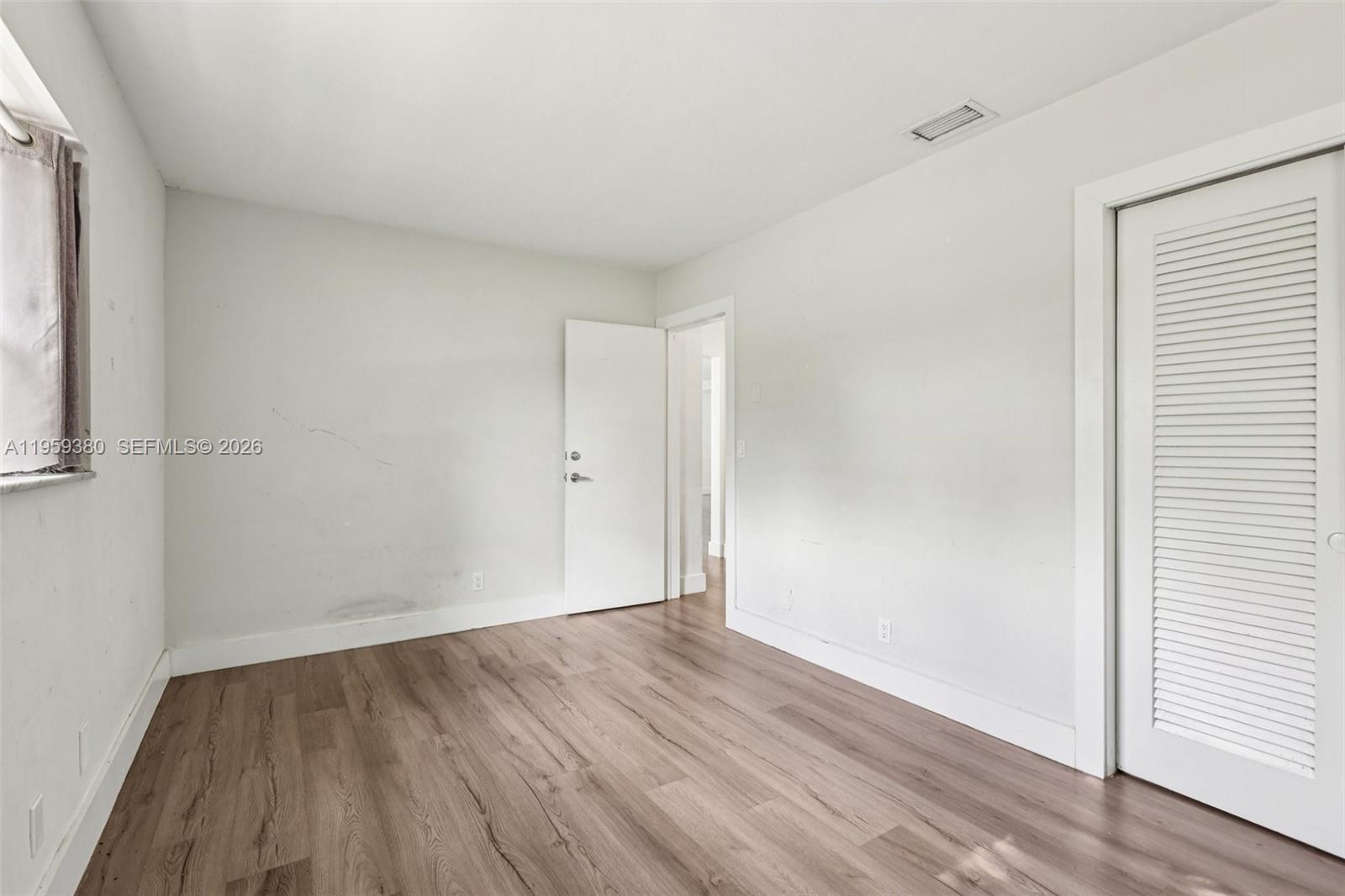 2720 Northeast 25th Terrace Boca Raton, FL 33431 - Photo 34 of 40 a view of an empty room with wooden floor and a window