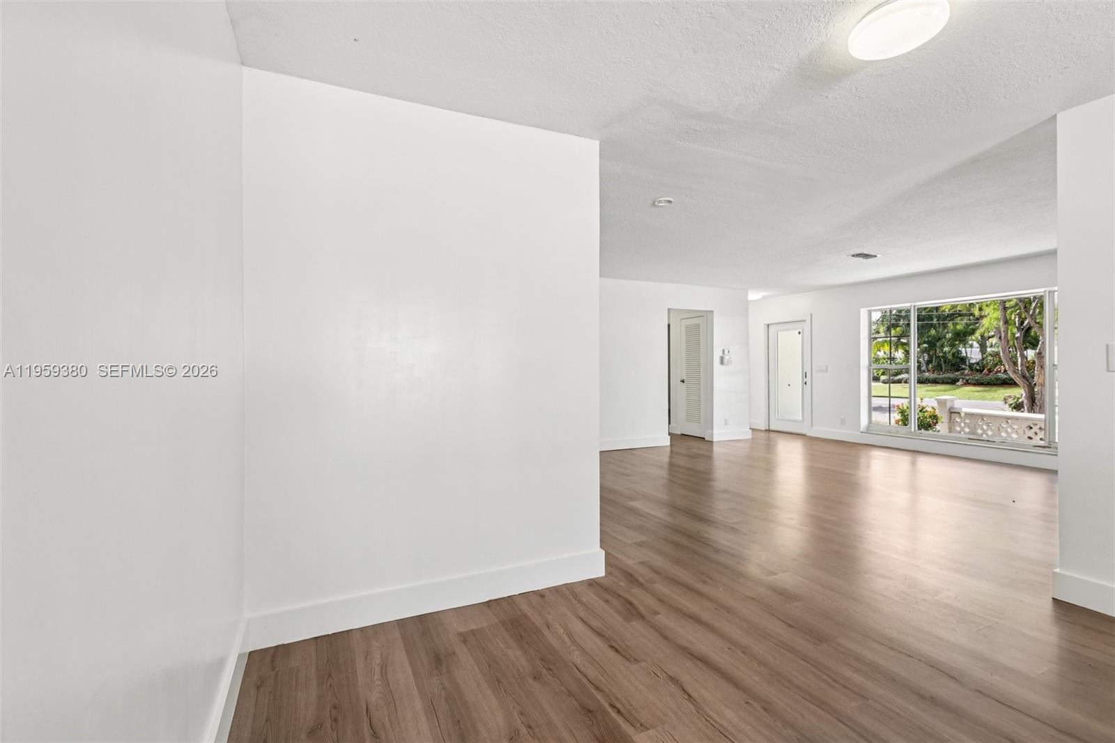 2720 Northeast 25th Terrace Boca Raton, FL 33431 - Photo 7 of 40 a view of an empty room with wooden floor and a window