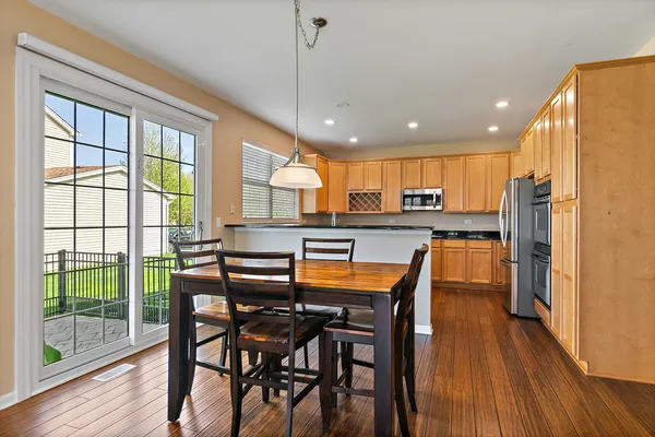 a kitchen with stainless steel appliances granite countertop wooden floor dining table and chairs