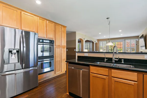 a kitchen with granite countertop a refrigerator a sink and white cabinets