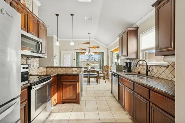 a kitchen with stainless steel appliances granite countertop a stove a sink and a refrigerator