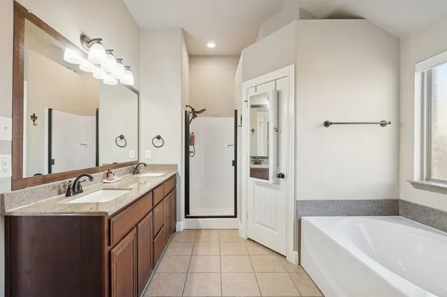 a spacious bathroom with a tub sink shower and mirror