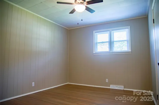 an empty room with a window and a chandelier fan