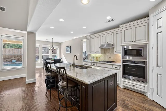 a kitchen with a stove a refrigerator and a dining table with wooden floor