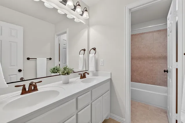 a bathroom with a double vanity sink a mirror and a bathtub