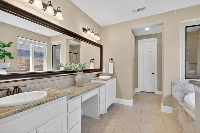a spacious bathroom with a granite countertop sink a mirror and a bathtub