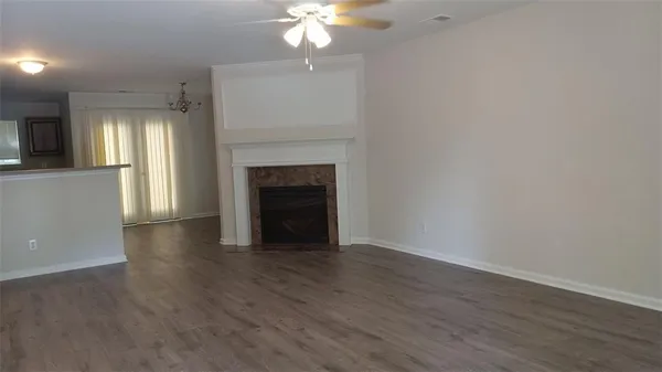 a view of an empty room with wooden floor and a fireplace
