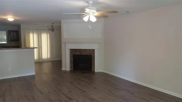 a view of a livingroom with a fireplace a ceiling fan and wooden floor