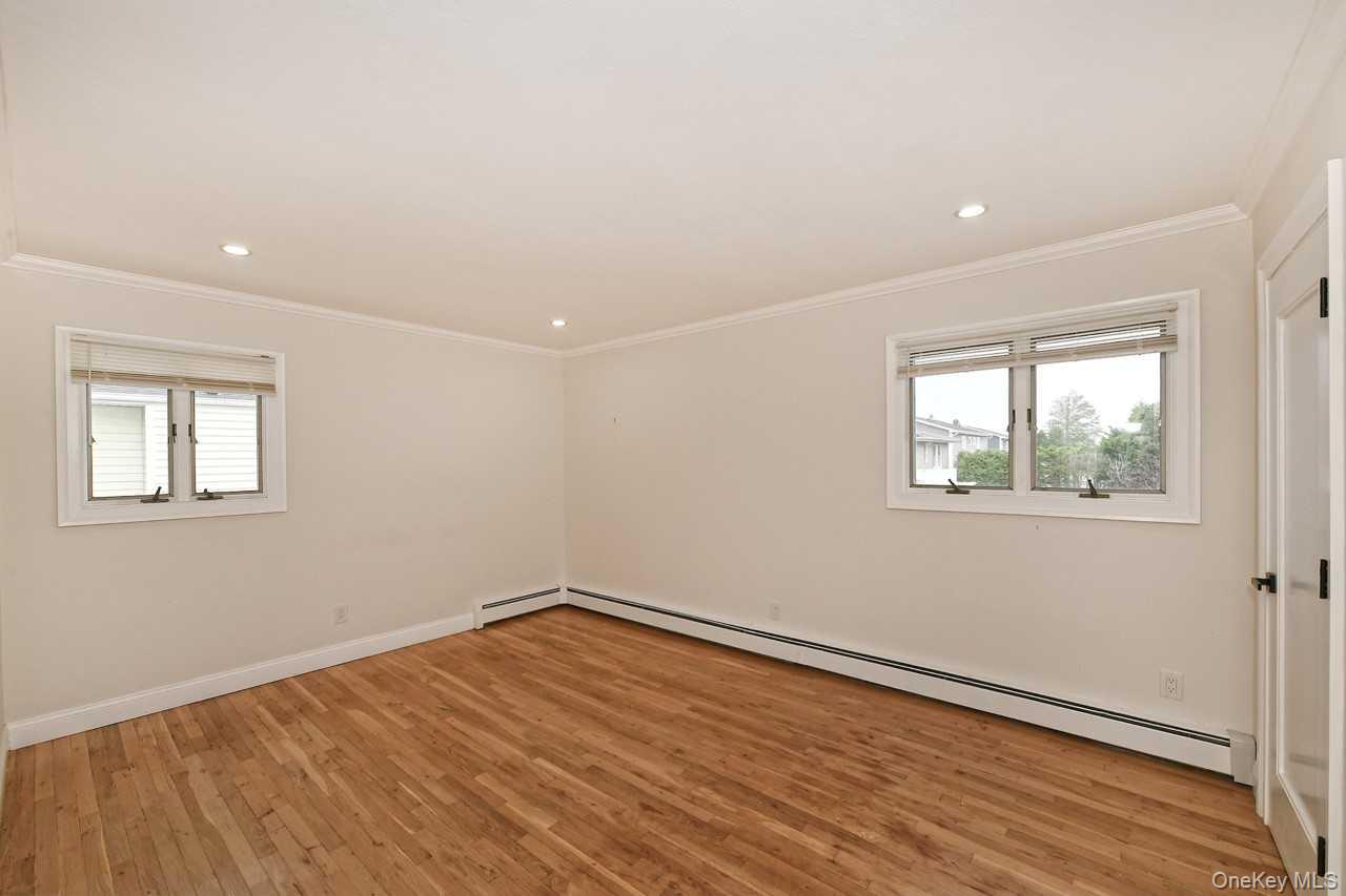 107 Beverly Road Massapequa, NY 11758 - Photo 23 of 41 a view of empty room with wooden floor and fan